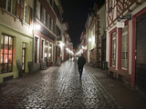 A Man Walks Down a Cobbled Street at Night