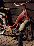 A Very Old Red Girls' Bike Rests on an Old Wooden Porch