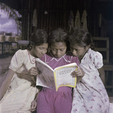 Three Sisters Look at a Copy of National Geographic Magazine