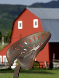 An Antique Tractor Seat in Front of Red Barn