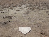Home Plate on Field of Dirt and Dead Grass