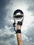 Football player holding helmet in air