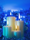 Lighted candle arrangement surrounded by Christmas decorations