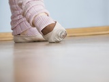 Young woman positions feet in ballet rehearsal