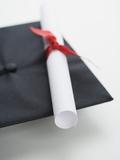 Close up of diploma and graduation cap