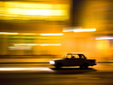 Panned Shot of Car at Night Passing Illuminated Buildings on the Malecon, Havana, Cuba