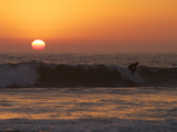 Surfer Riding a Wave at Sunset over the Pacific Ocean