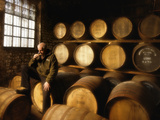 A Worker Tastes Whisky in a Distillery Surrounded by Aging Barrels