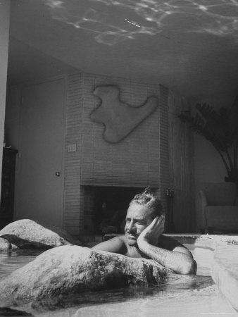 Industrial Designer Raymond Loewy Relaxing in Rock Filled Pool at His Home
