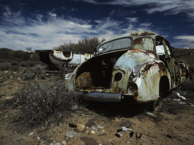 Antique Car Wrecks Discarded and Rusting Away under a Vast Desert Sky