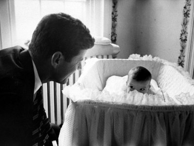 Sen. John F. Kennedy Playing Peek-A-Boo with His Daughter Caroline in Her Crib Stretched Canvas Print