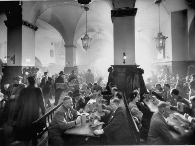 The Hofbrauhaus with Patrons Sitting at Long Tables Holding Large Steins of Beer Stretched Canvas Print