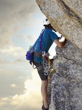 Young man rock climbing up a vertical cliff