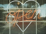 Neon 'Open' sign framed in a heart-shape in a window