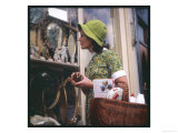 Woman in a Green Floppy Hat and Green Dress Browses in a Shop Selling Various Mirrors and Ornaments