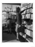 Two Women Both Wearing Box Pleated Skirts Browse Around a Bookshop