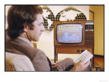 Fashionable Young Man in a Beige Jacket Adjusts His Television with the Aid of the Latest Gadget