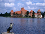 Boy Fishing from Lakeside Pier with Trakai Island Castle Behind  Trakai  Lithuania 