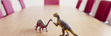 Two Dinosaur Toys on a Conference Table