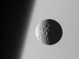This Amazing Perspective View Captures Battered Moon Mimas Against the Hazy Limb of Planet Saturn