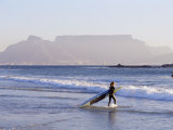 Young Woman Surfer Enters the Water of the Atlantic Ocean with Table Mountain in the Background