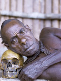 Portrait of an Asmat Tribesman Leaning on a Human Skull  Irian Jaya  Indonesia