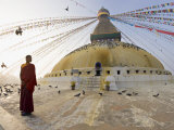 Young Buddhist Monk Turns to Look at the Dome of Boudha Tibetan Stupa in Kathmandu  Asia