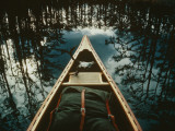 Bow of a Canoe Set against Trees Reflected in the Still Water
