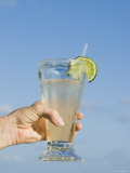 Lemonade  Lime and Straw Held in Womens Hand with Blue Sky Background  Ambergris Caye  Belize