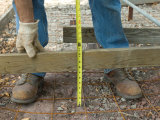 Man Measures a Wood Frame Before Pouring Concrete