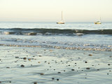 Pebbles in Wet Sand with Small Waves and Sail Boats in the Background  California