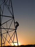 Silhouette of a Man Climbing a High Power Electric Line Tower  California