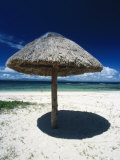 Thatch Palapa Umbrella on Beach with People Walking Next to the Sea