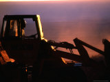 Silhouette of a Man Operating Tractor at Sunset