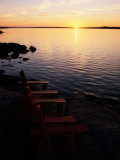 Two Empty Wooden Chairs Sit on Maine's Rocky Coast as the Sun Sets over the Horizon