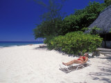 Woman Relaxing on a White Sand Beach in Front of a Bure Hut