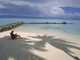 Woman Reads in Solitude on a Quiet Beach Next to Turquoise Water