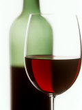 Red Wine Glass with Half-Full Wine Bottle in Background