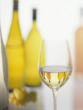 A Glass of White Wine and Wine Bottles in Background
