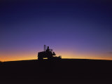 Silhouette of Worker Cutting Grass at Sunrise