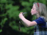 A Young Girl Plays Out a Fairy Tale as She Prepares to Kiss a Frog