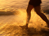 Close View of a Runners Legs Splashing Through the Surf