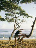 A Woman Stretches Her Body on a Small Tree at a Sandy Beach