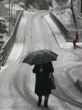 Older Woman Walking in the Snow with an Umbrella