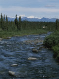 Mountain Stream with Cabin in Evergreen Forest in Distance