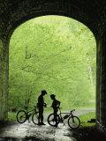 Two Silhouetted Cyclists Stop in a Tunnel on a Bike Trail