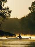 A Kayaker Paddles the River in a Morning Mist