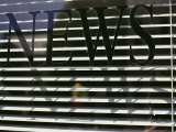 Afternoon Sun Casts Shadows Across the Word News Painted on a Window