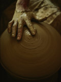 Close-up of the Brown Muddy Hand of a Potter as He Spins a Clay Pot on His Wheel