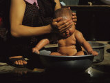 A Bhutanese Woman Bathes Her Baby in a Large Metal Bowl